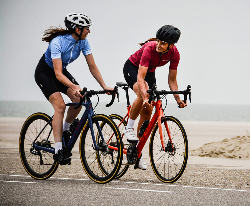 Two women cycling by the beach