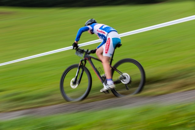 Man in athletic cycling gear riding a bicycle downhill