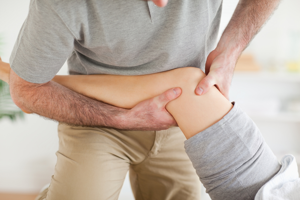 Physical therapist performing physical therapy on a patient’s knee