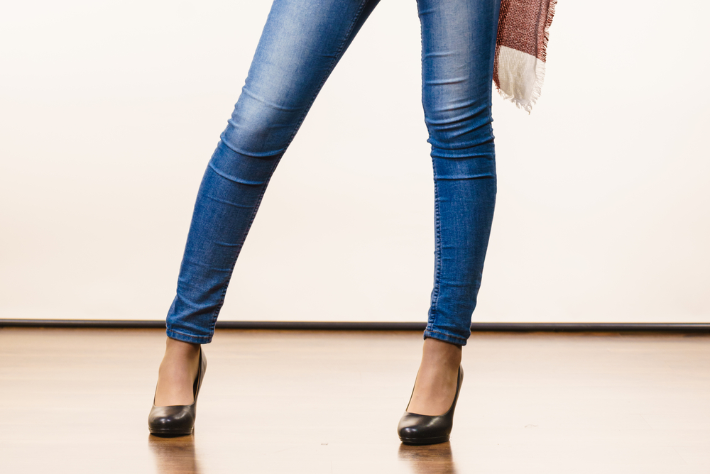 the legs of a woman wearing high heels and skinny jeans