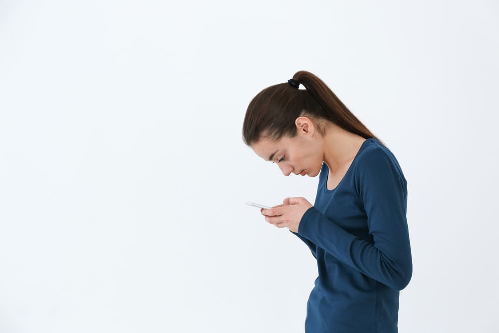 a woman with her head bent down to look at her mobile phone