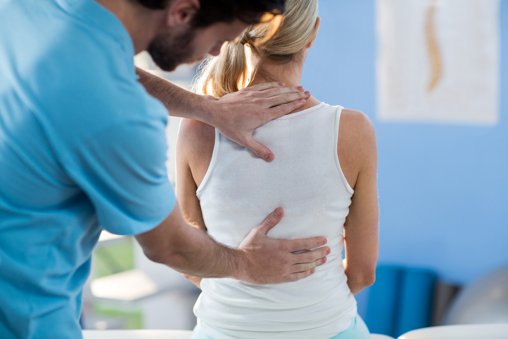 A physical therapist helps a woman with back pain