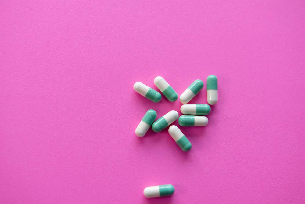 Blue and white pills on a pink background
