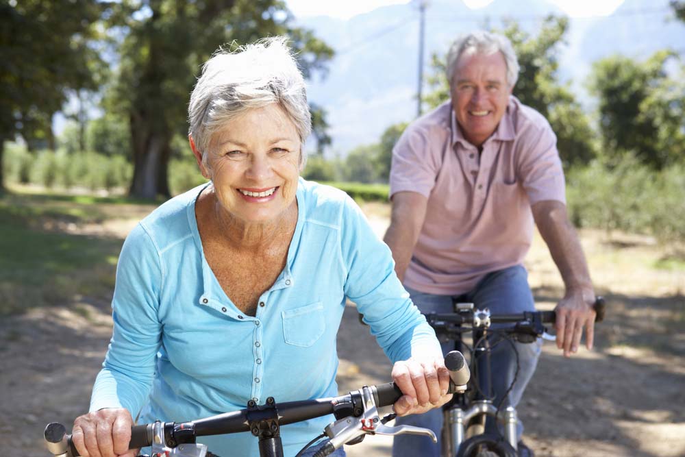 A senior couple on a bike ride outdoors, facing the camera.