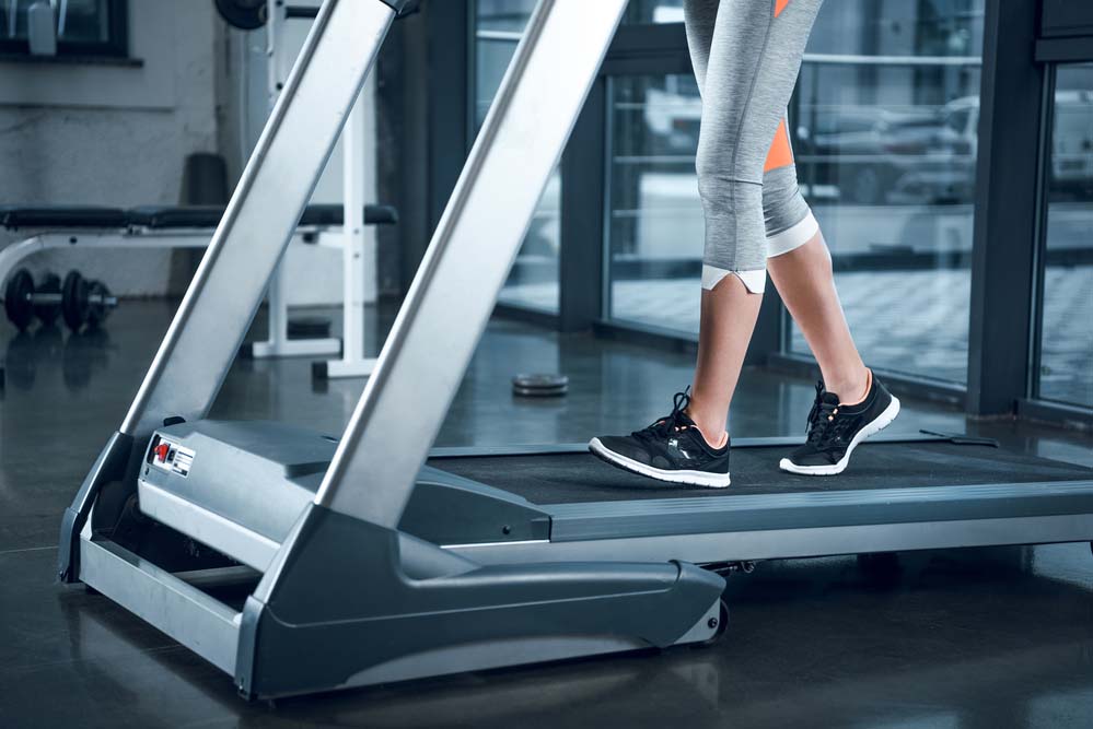 An image of a woman's feet and lower legs walking on a treadmill.