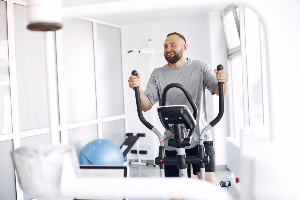 Bearded man using spin bike in physiotherapy room